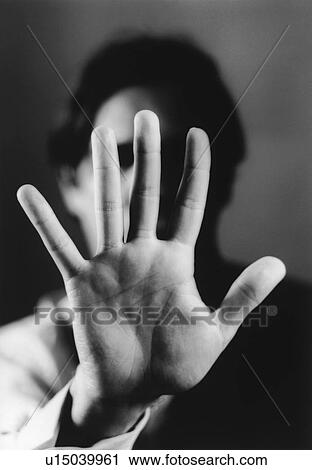 Stock Image - Man holding up hand, close-up of palm of hand, (b&w). Fotosearch