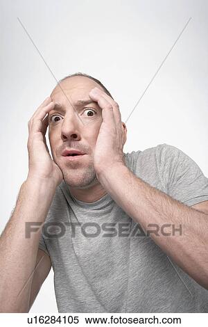 Stock Photography - Man hunching down, covering face with hands in fear. Fotosearch