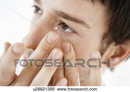 Stock Photo - Man inserting contact lens, close up. Fotosearch