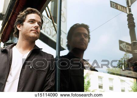 Stock Image - Man leaning against shop window. Fotosearch