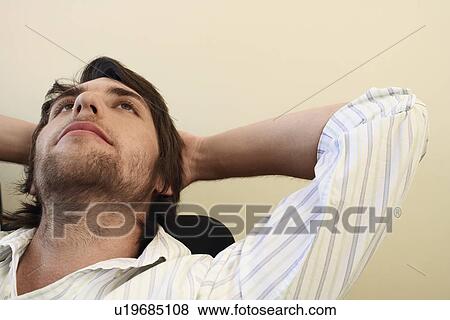 Stock Photo - Man leaning back on chair with Hands Behind Head.. Fotosearch