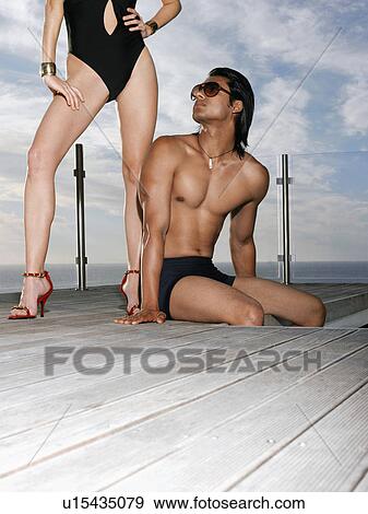 Man looking up at woman in bathing suit on pool deck View Large Photo Image Stock Photo - Man looking up at woman in bathing suit on pool deck. Fotosearch