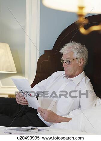 Man lying on bed reading document View Large Photo Image Stock Photography - Man lying on bed reading document. Fotosearch