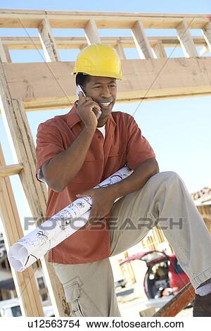 Man on building site on cell phone View Large Photo Image Picture - Man on building site on cell phone. Fotosearch