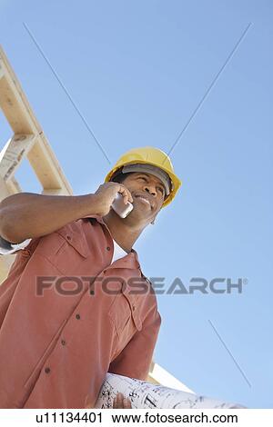 Man on building site on cell phone, half length View Large Photo Image Stock Image - Man on building site on cell phone, half length. Fotosearch