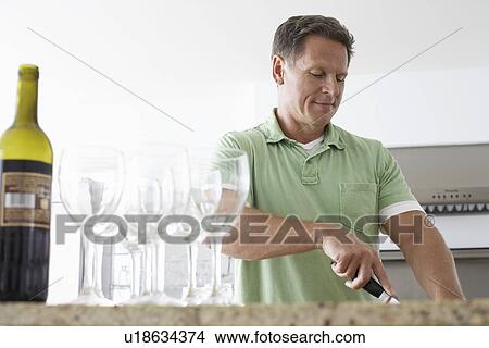 Man preparing food by wine glasses in kitchen View Large Photo Image Picture - Man preparing food by wine glasses in kitchen. Fotosearch