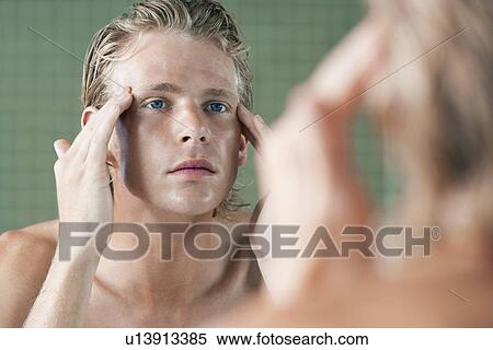 Stock Photography - Man rubbing temples in front of mirror. Fotosearch