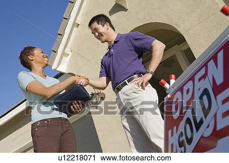 Man shaking hands with estate agent outside their new home View Large Photo Image Stock Image - Man shaking hands with estate agent outside their new home. Fotosearch