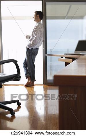 Man standing in home office, leaning on sliding door, side view. View Large Photo Image Picture - Man standing in home office, leaning on sliding door, side view.. Fotosearch