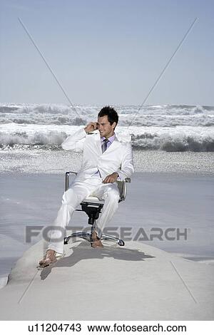 Man using mobile phone sitting on office chair on beach View Large Photo Image Stock Image - Man using mobile phone sitting on office chair on beach. Fotosearch