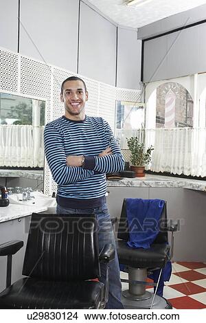 Picture - Man with arms crossed in barbers shop, smiling, portrait. Fotosearch