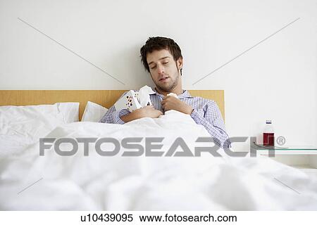 Man with cold in bed holding box of tissues View Large Photo Image Stock Photography - Man with cold in bed holding box of tissues. Fotosearch