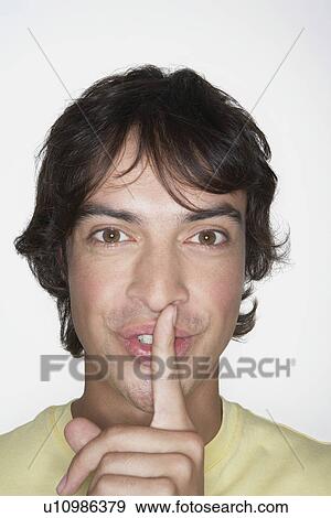 Stock Photo - Man with Finger on Lips, grinning, close-up. Fotosearch