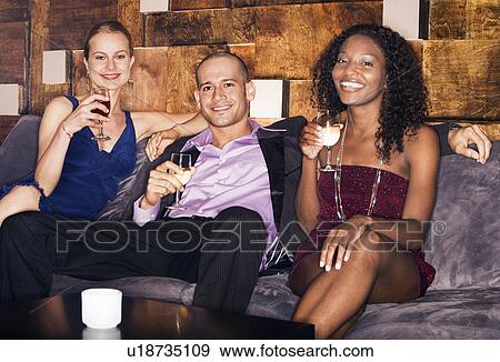 Man with two women sitting on couch in bar View Large Photo Image Stock Photo - Man with two women sitting on couch in bar. Fotosearch