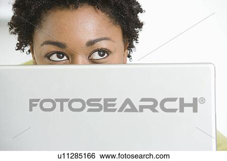 Mid-adult business woman peeking from behind laptop View Large Photo Image Stock Photograph - Mid-adult business woman peeking from behind laptop. Fotosearch