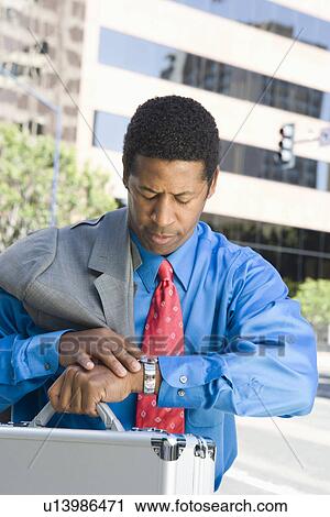 Stock Image - Mid-adult businessman checking time. Fotosearch