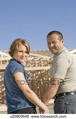 Stock Photo - Mid-adult couple at construction site, portrait. Fotosearch
