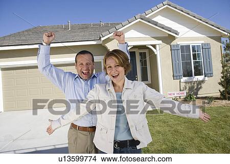 Picture - Mid-adult couple celebrating house ownership. Fotosearch