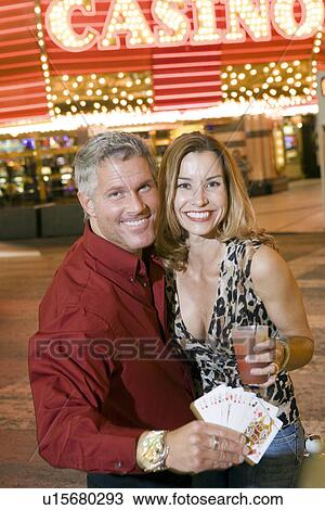 Stock Image - Mid-adult couple in front of casino building, portrait. Fotosearch