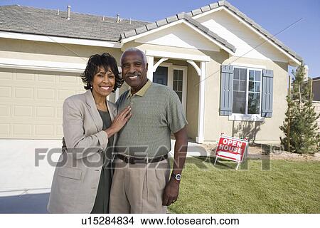 Picture - Mid-adult couple in front of new house, portrait. Fotosearch