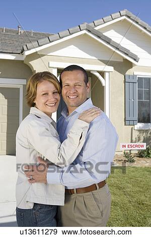 Stock Photo - Mid-adult couple in front of new house, portrait. Fotosearch