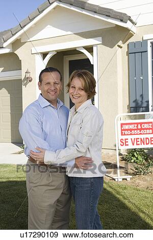 Stock Photo - Mid-adult couple in front of new house, portrait. Fotosearch