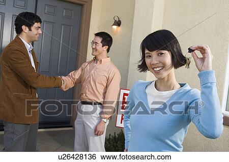 Stock Photograph - Mid adult couple in front of their new home. Fotosearch