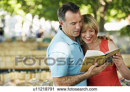 Mid-adult couple in park looking at book together View Large Photo Image Stock Image - Mid-adult couple in park looking at book together. Fotosearch