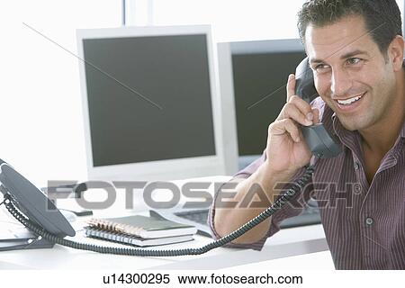 Stock Photography - Mid-adult male office worker on the phone. Fotosearch
