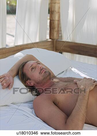 Mid-adult man lying down on bed outside View Large Photo Image Stock Photograph - Mid-adult man lying down on bed outside. Fotosearch