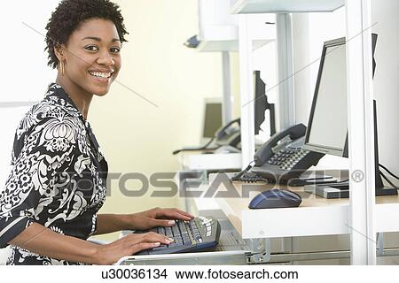 Picture - Mid-adult office worker sitting by desk. Fotosearch