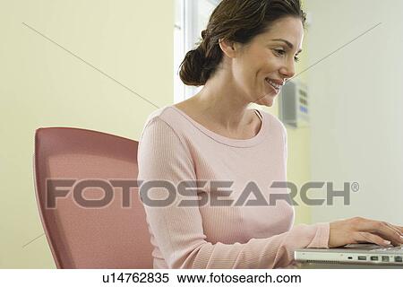 Stock Photography - Mid-adult office worker using laptop. Fotosearch