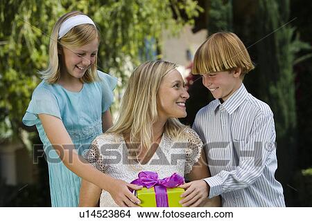 Picture - Mid-adult woman receiving birthday present from her son and daughter. Fotosearch