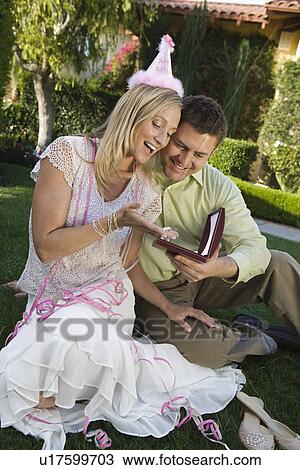 Stock Image - Mid-adult woman receiving pearl necklace as birthday present. Fotosearch