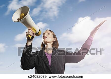 Stock Photo - Mid-adult woman shouting through megaphone outside. Fotosearch