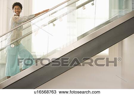 Stock Image - Mid-adult woman walking up stairs. Fotosearch