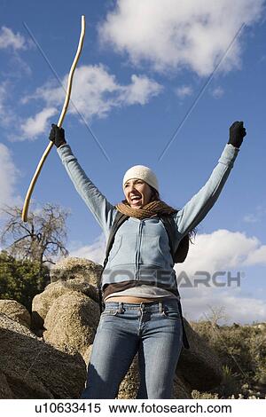 Stock Photography - Mid adult woman with hands raised, cheering. Fotosearch