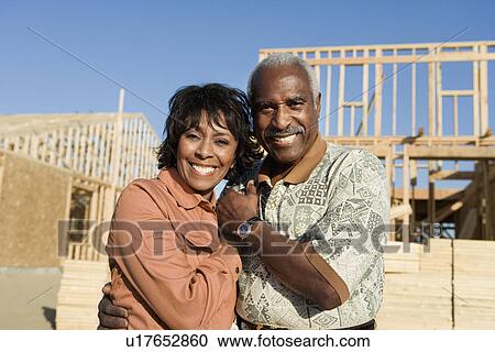 Middle-aged couple in front of home construction site, portrait View Large Photo Image Stock Image - Middle-aged couple in front of home construction site, portrait. Fotosearch