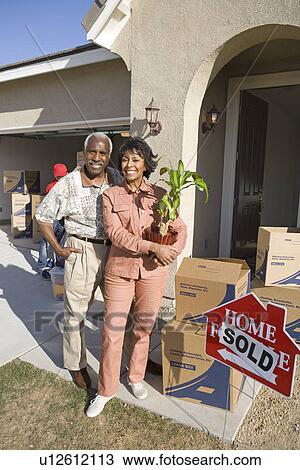 Stock Image - Middle-aged couple in front of new house. Fotosearch