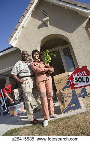 Stock Photography - Middle-aged couple in front of their new house. Fotosearch