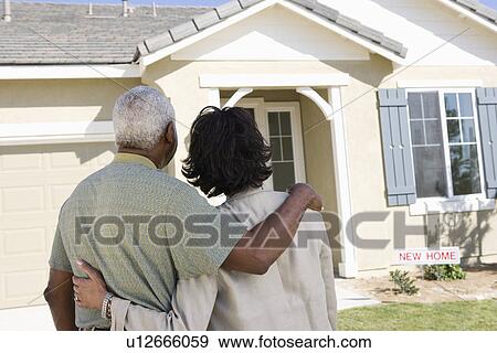 Stock Photo - Middle-aged couple looking at house, back view. Fotosearch
