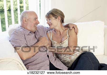 Middle Aged Couple sitting on sofa View Large Photo Image Stock Photo - Middle Aged Couple sitting on sofa. Fotosearch