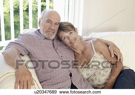 Stock Photo - Middle Aged Couple sitting on sofa. Fotosearch