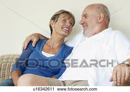 Stock Image - Middle Aged Couple sitting on wicker chair. Fotosearch