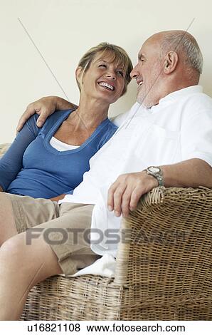 Middle Aged Couple sitting on wicker chair View Large Photo Image Stock Photo - Middle Aged Couple sitting on wicker chair. Fotosearch