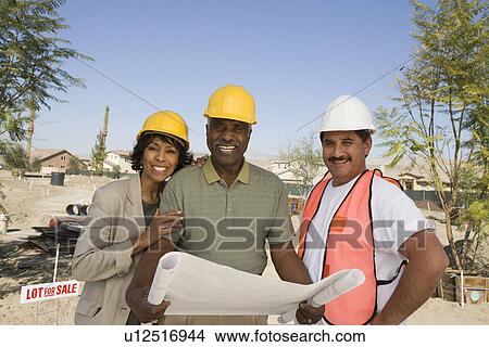 Middle-aged couple watching blueprints with surveyor, portrait View Large Photo Image Picture - Middle-aged couple watching blueprints with surveyor, portrait. Fotosearch