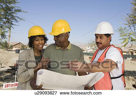 Stock Photo - Middle-aged couple watching blueprints with surveyor. Fotosearch