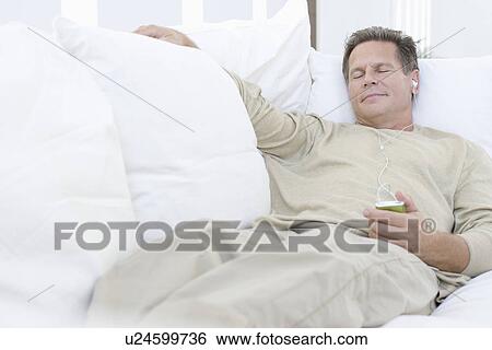 Middle-aged man listening to music on sofa View Large Photo Image Stock Photograph - Middle-aged man listening to music on sofa. Fotosearch