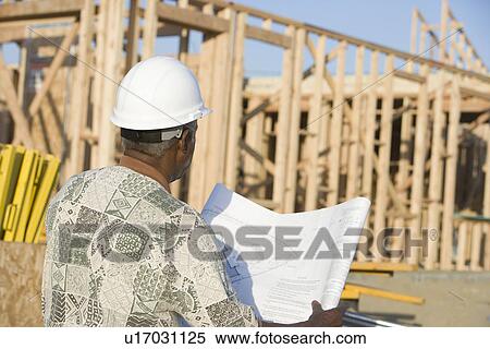 Middle-aged man with blueprints, construction site, back view View Large Photo Image Stock Photography - Middle-aged man with blueprints, construction site, back view. Fotosearch