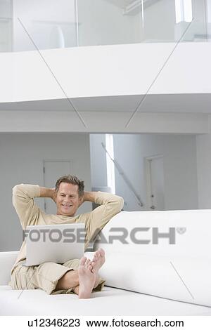 Middle-aged man with laptop on sofa View Large Photo Image Stock Image - Middle-aged man with laptop on sofa. Fotosearch